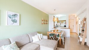 Een moderne woonkamer met een bank, een eettafel en een keuken op de achtergrond.