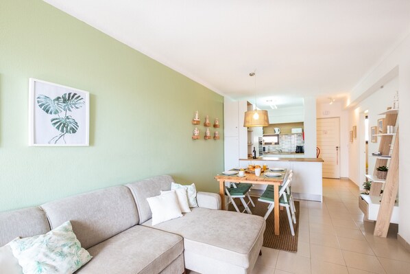 Una sala de estar moderna con un sofá, una mesa de comedor y una cocina al fondo.