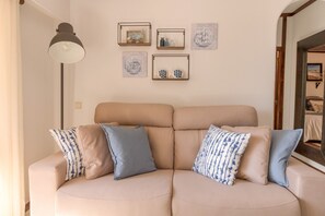 Ein beiges Sofa mit vielen Kissen in einem Raum mit einer hellen Wand.