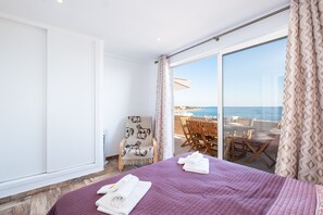 Ein Zimmer mit Bett, Stuhl und Meerblick.