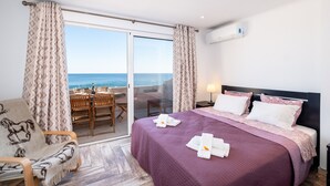 Een hotelkamer met een bed, een stoel, een tafel en uitzicht op de oceaan.