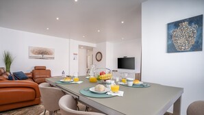 A modern dining area with a long table, chairs, and a television on the wall. - #034 Tebay by Home Holidays (Albufeira)