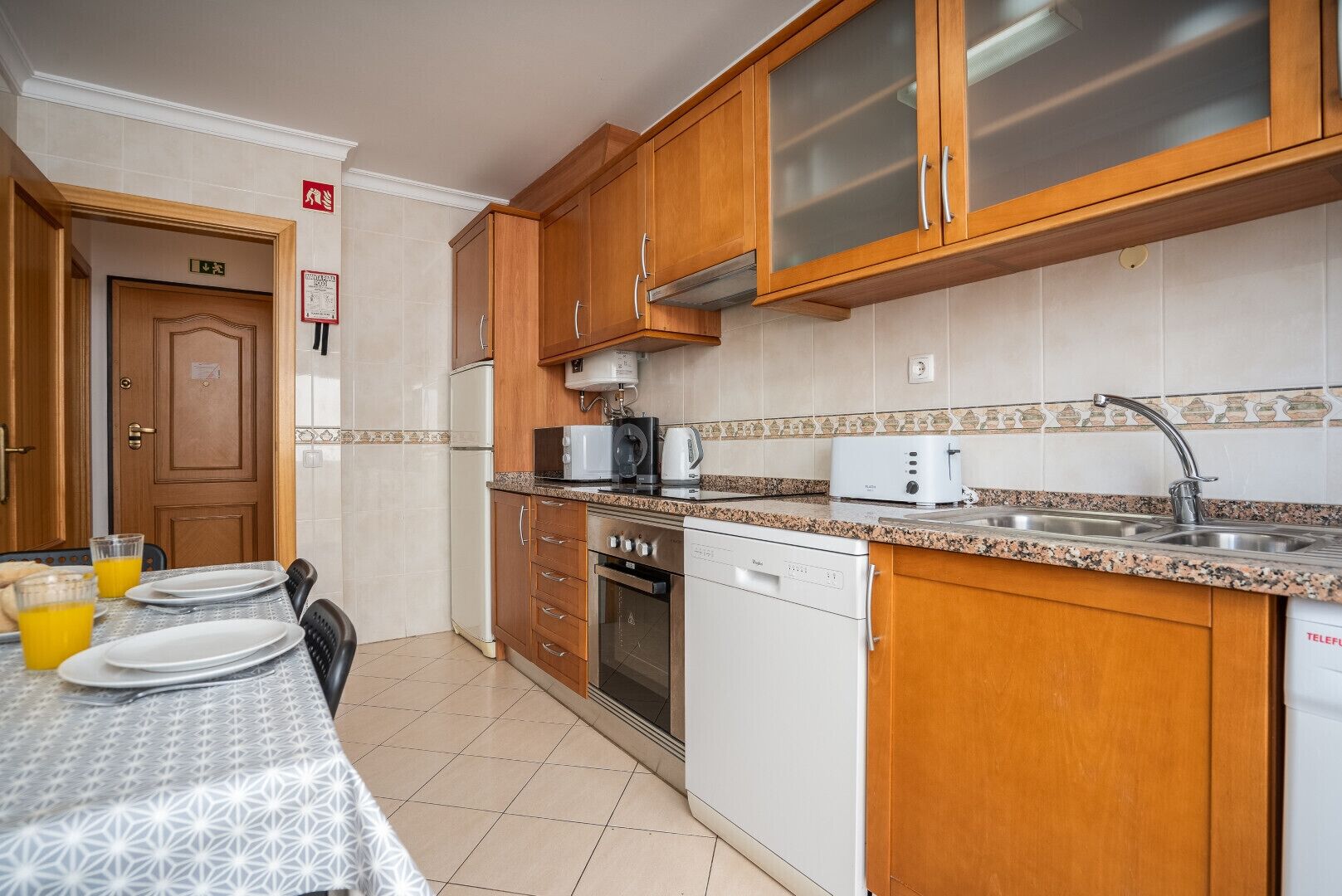 A compact kitchen with wooden cabinets, a microwave, a toaster, and a dishwasher.