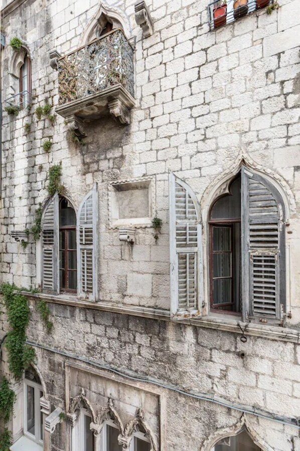 A historic building with arched windows, a balcony with ornate metalwork, and stone walls. - 4 stars Stone Walls' - Sunny, cozy Studio right in the centre of Split (Split)