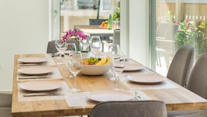 A dining table set with plates, cutlery, and wine glasses, with a bowl of fruit and a vase of flowers. - Villa Elena Deluxe with whirlpool and POOL by the SEA (Fažana)