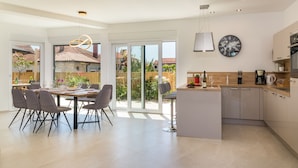 A modern kitchen with a central island, large windows, and a dining area with chairs. - Villa Elena Deluxe with whirlpool and POOL by the SEA (Fažana)