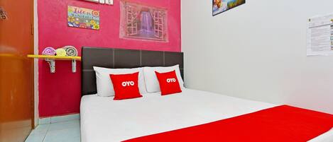 A bed with white and red bedding, a red throw blanket, and two red pillows with 'OYO' text.