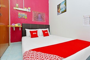 Een bed met wit en rood beddengoed, een rode plaid en twee rode kussens met de tekst 'OYO'.