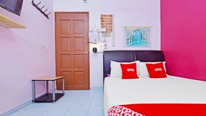 Un dormitorio con cama, una mesita, una puerta y un aplique de pared.