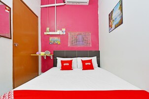 A room with a bed, a window with a view, a wall-mounted air conditioner, and a door.