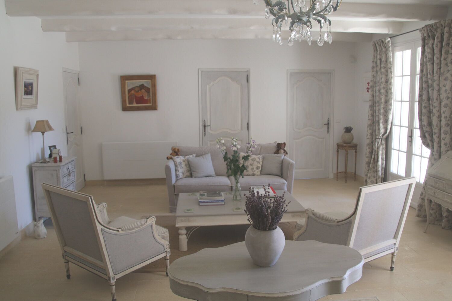 Un salon spacieux comprenant un canapé, deux fauteuils, une table basse et un lustre.
