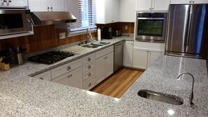 Una cocina moderna con encimeras de granito, electrodomésticos de acero inoxidable y armarios de madera.