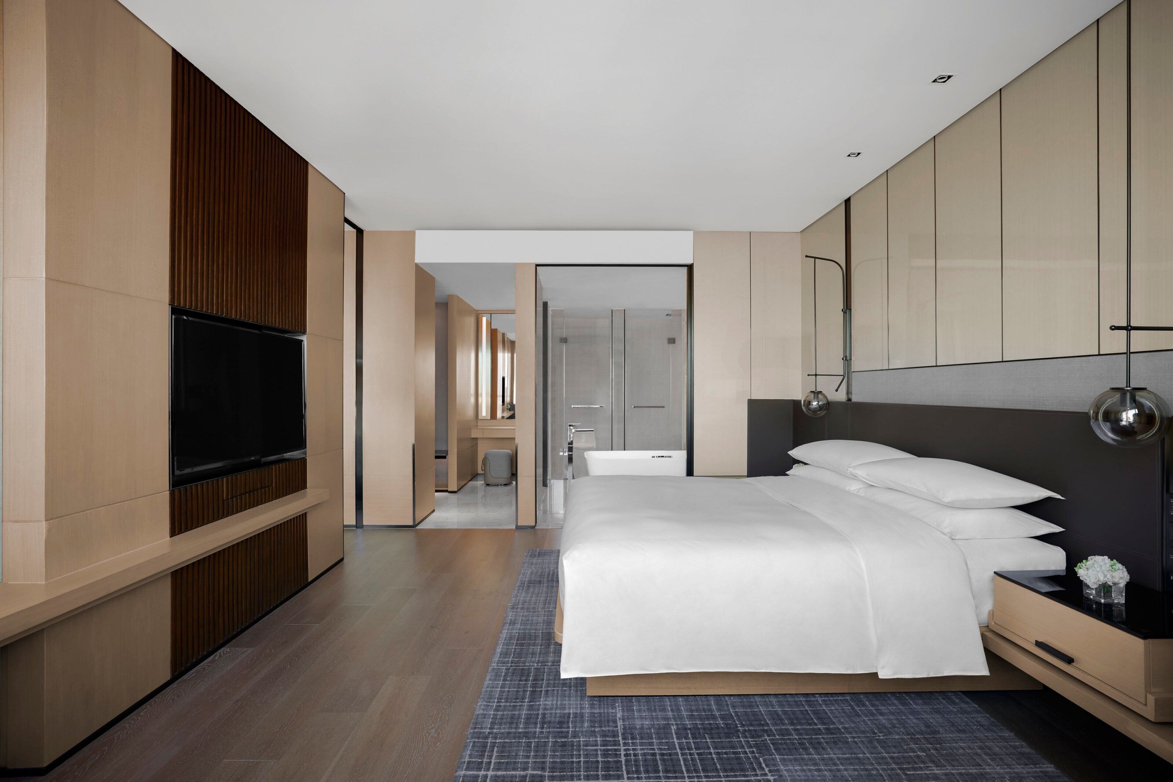 A modern hotel room with a large bed, a flat-screen TV, and a walk-in closet.
