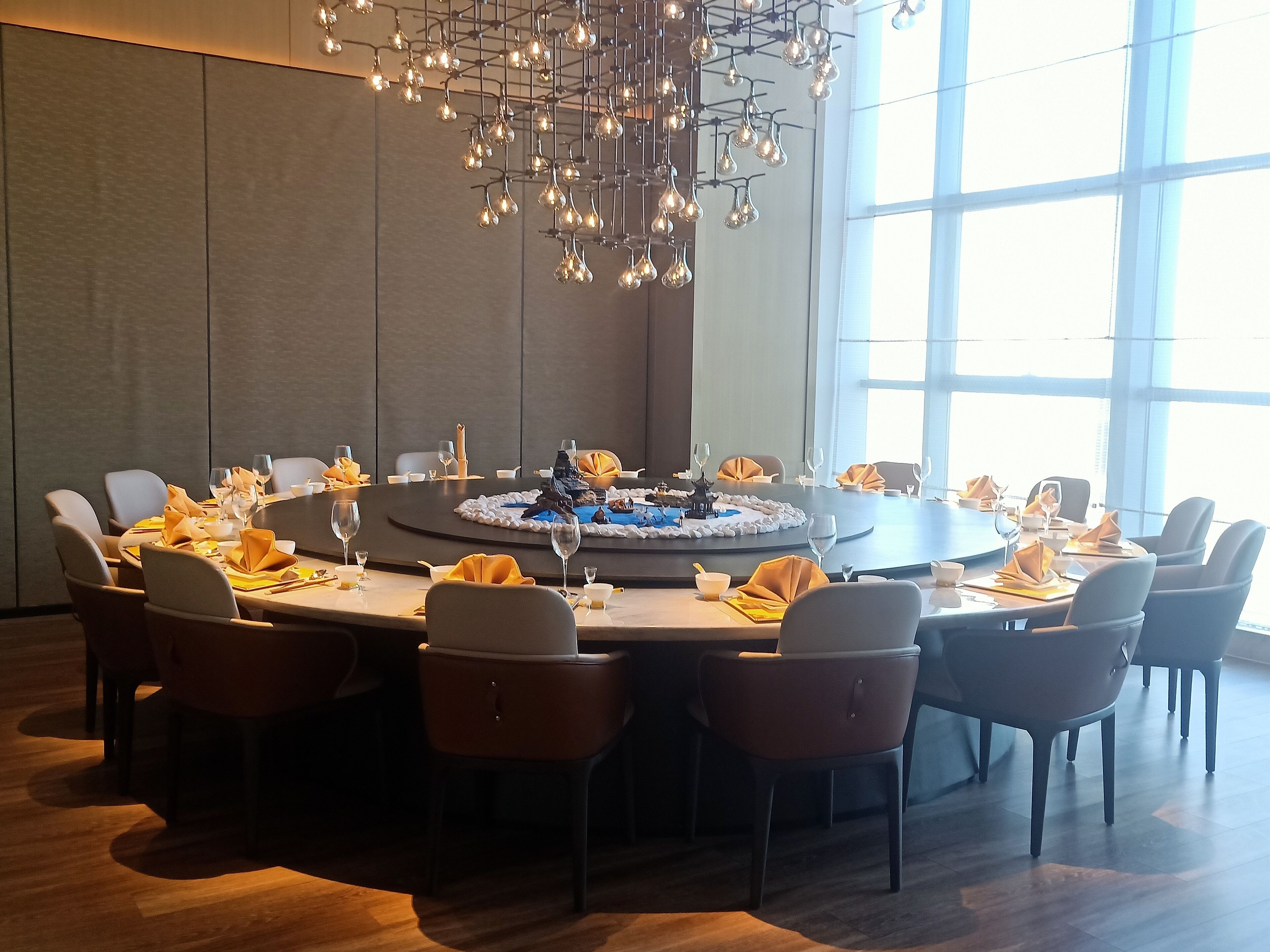 A conference room with a round table, chairs, and a modern chandelier.