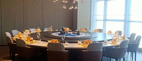 A conference room with a round table, chairs, and a modern chandelier.