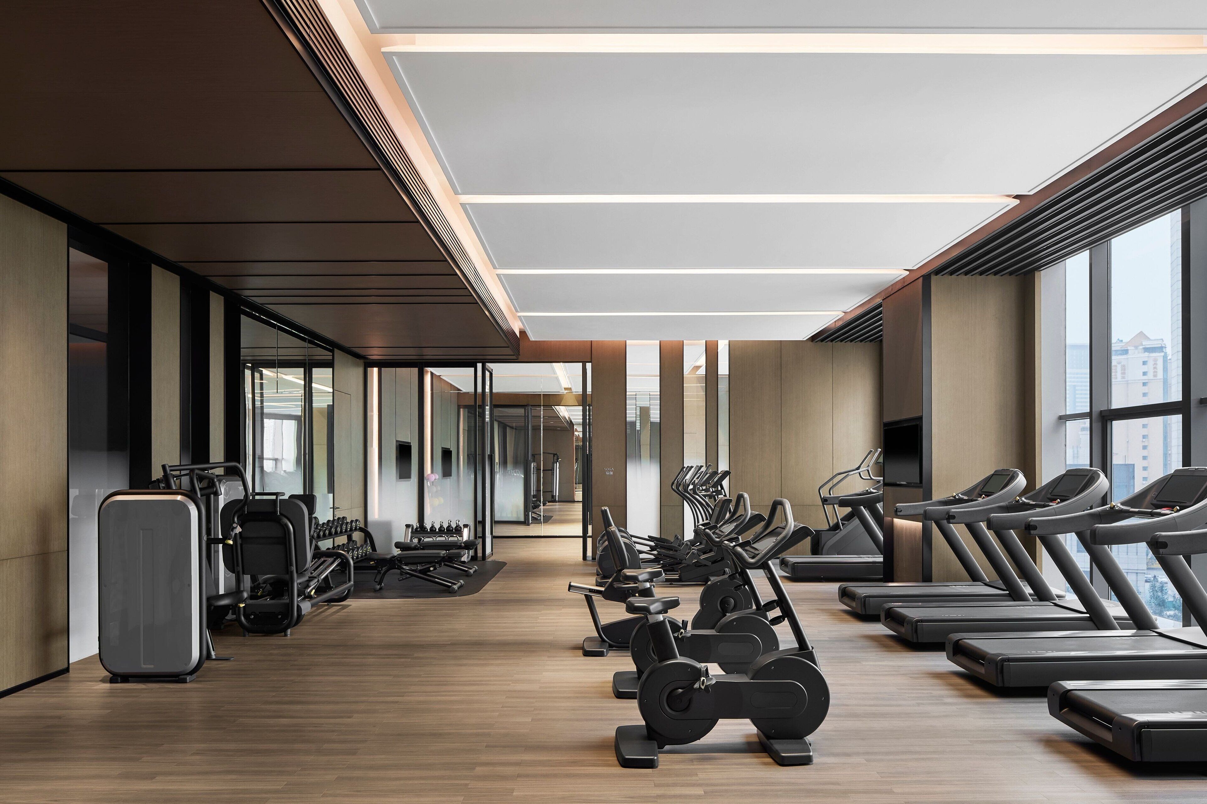 A modern gym with treadmills, elliptical machines, and weight stations.