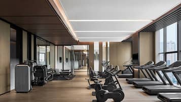 A modern gym with treadmills, elliptical machines, and weight stations.