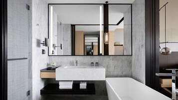 Un baño moderno con un espejo grande, una bañera, un tocador con lavamanos y un perchero para toallas.