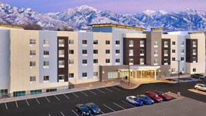 A hotel with a modern design, featuring a parking lot and a view of snow-capped mountains in the background. - TownePlace Suites by Marriott Salt Lake City Murray (Murray)