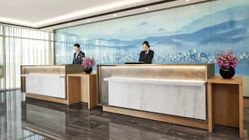 A reception area with two reception desks, a large glass wall with a mountain landscape, and a polished floor.
