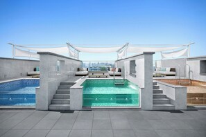 A rooftop swimming pool with a city view, surrounded by modern architecture and outdoor seating areas. - Daegu Marriott Hotel (Daegu)