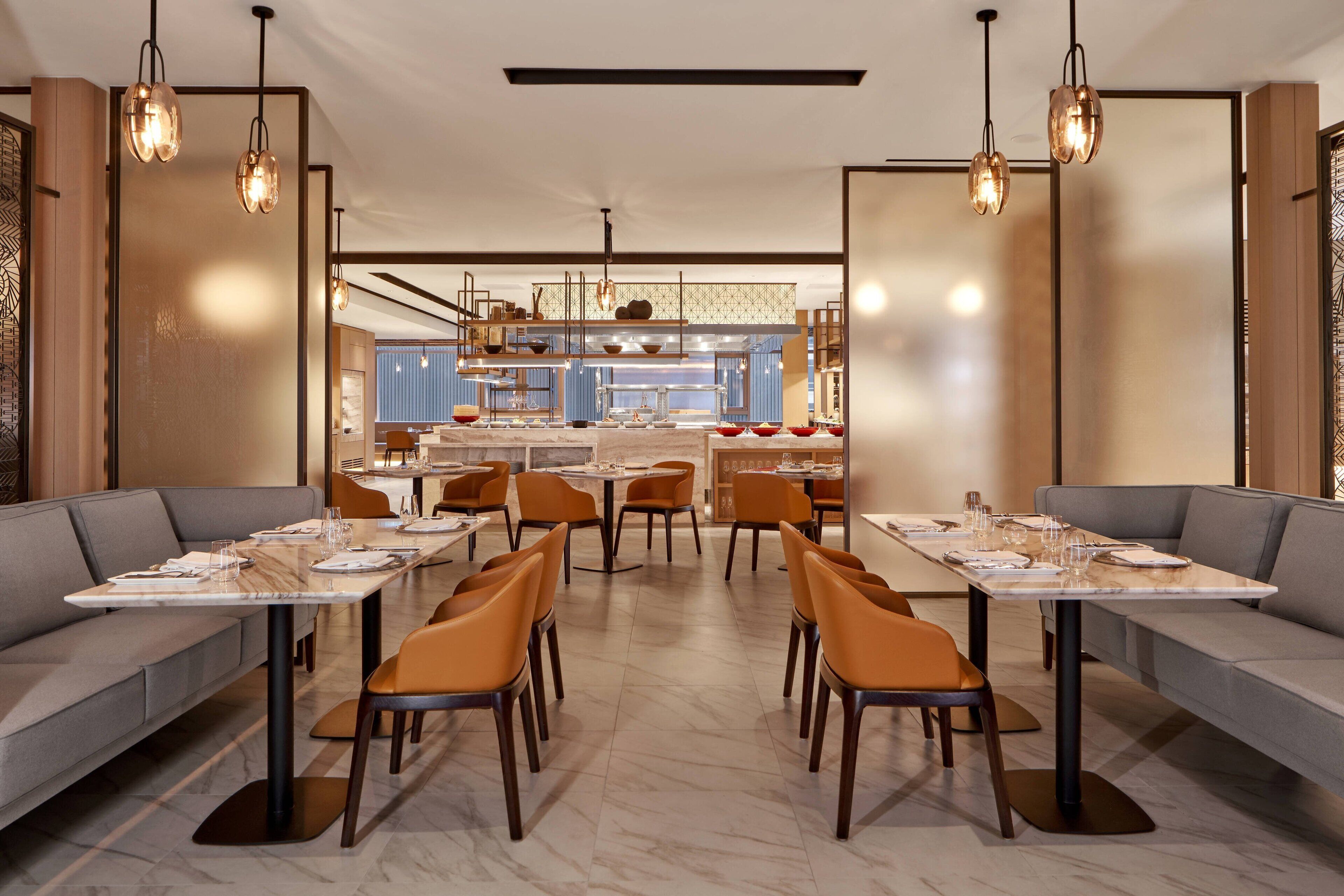 A modern dining area with tables and chairs, a central bar area, and a seating area with sofas.