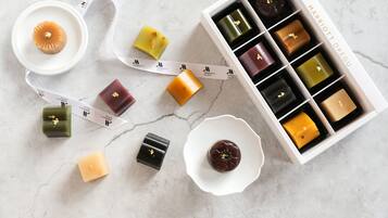 Una colección de velas de cera de distintas formas y colores, con una caja blanca que indica "MARRIOTT DAEGU" al fondo.