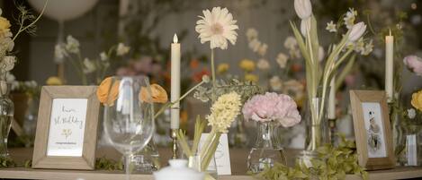 Una mesa decorada con jarrones de vidrio con flores, velas y tarjetas de cumpleaños enmarcadas.