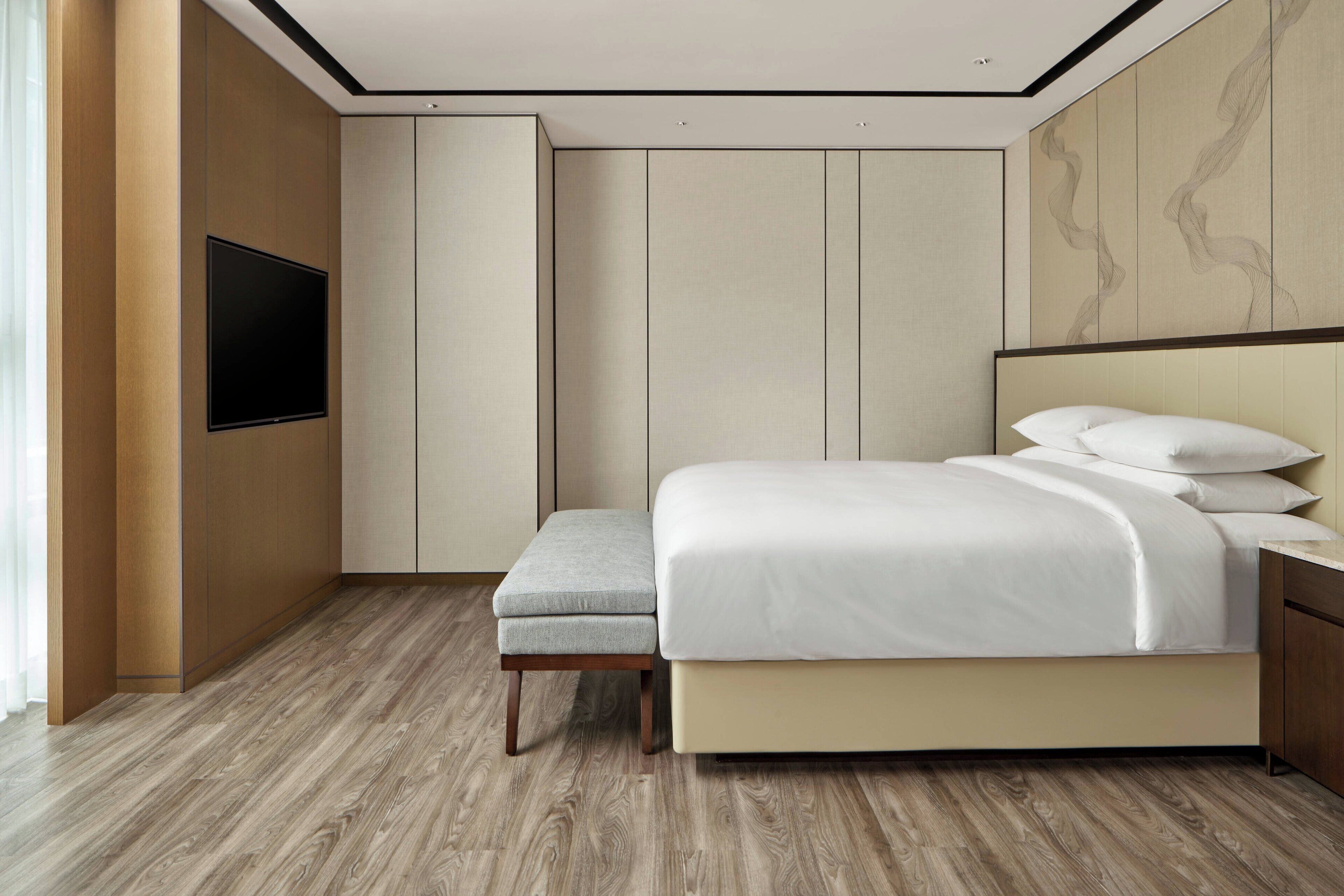 Habitación de hotel moderna con una cama grande, un televisor de pantalla plana en la pared y piso de madera.