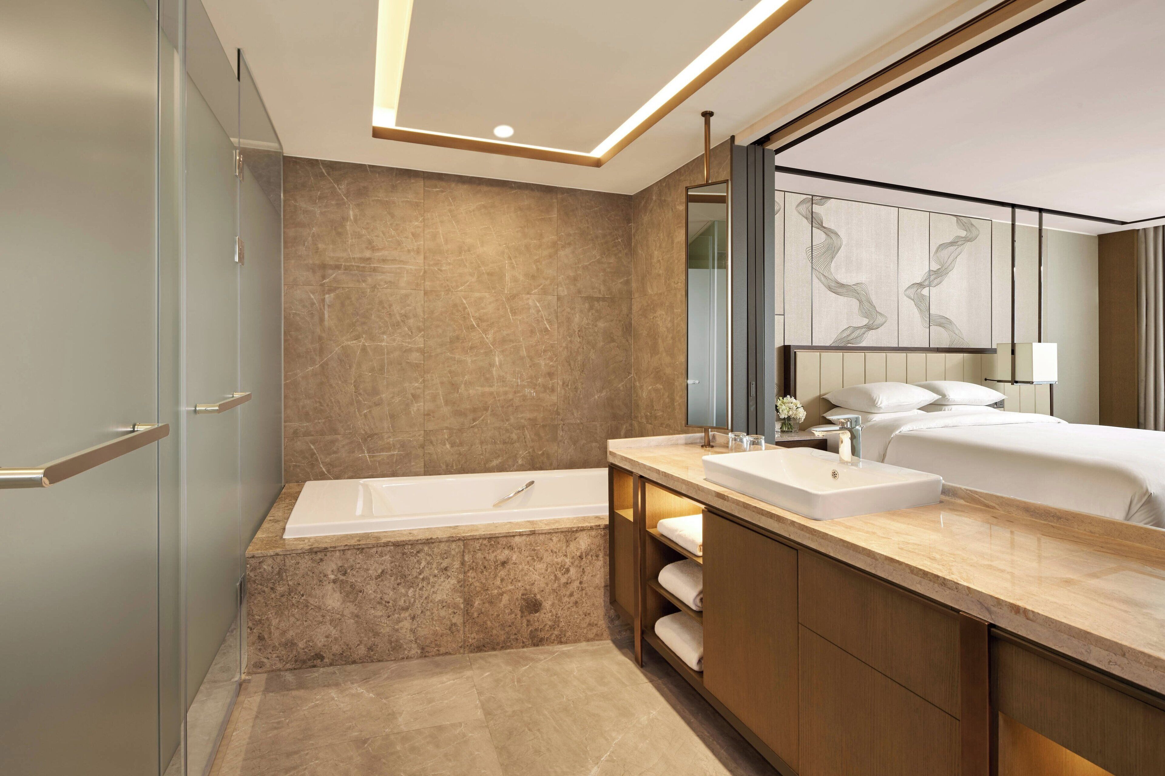 A modern bathroom with a bathtub, vanity, and a large mirror.