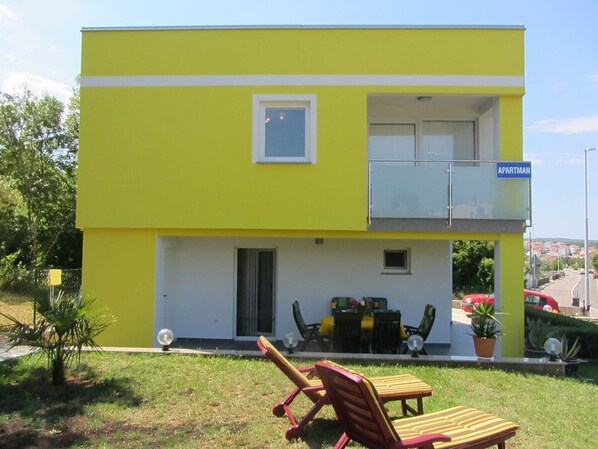 Un edificio giallo di due piani con un balcone, una piccola finestra e un cartello con scritto 