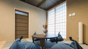 A tatami mat room with a round table, blue cushions, a vase with flowers, and a shoji screen door. - No.8 Kyoto (Kyoto)