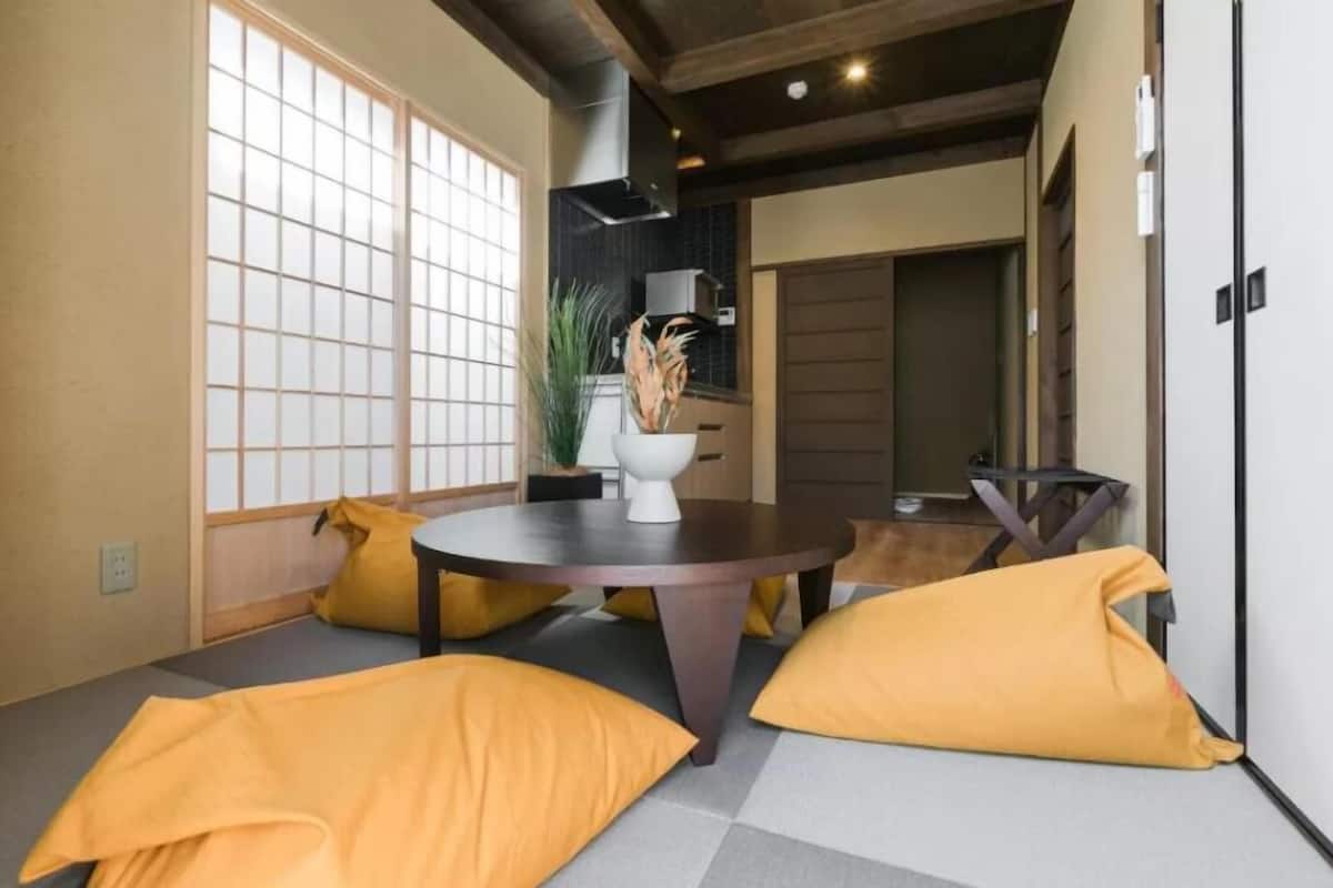 Decoração moderna com mesa redonda, almofadas amarelas e um vaso decorativo.