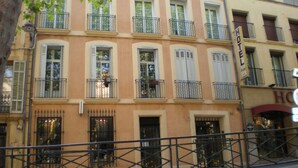 A multi-story hotel with balconies, a visible sign indicating it is a hotel, and a number '66' on the facade. - Town center with terrace (Aix-en-Provence)