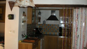 A kitchen with wooden cabinets, a tiled backsplash, and a hanging light fixture. - Town center with terrace (Aix-en-Provence)