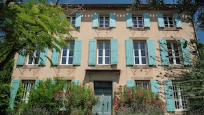 A building with a symmetrical facade, multiple windows with shutters, and a central entrance.