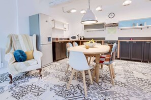 Eine moderne Küche mit Essbereich, ausgestattet mit einem runden Tisch, Stühlen, einer Couch und einem gemusterten Boden.