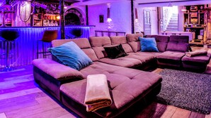 A modern living room with a sectional sofa, a bar area, and a staircase leading to an upper level.