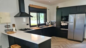 A modern kitchen with a central island, black cabinetry, stainless steel appliances, and a herringbone wood floor. - VILLA OASIS : Ideal for families and groups. (Arcos De La Frontera)