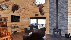 Un interior de madera con chimenea, monturas de animales y una zona de estar acogedora.