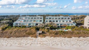 Une propriété située en bord de mer, comprenant plusieurs bâtiments, une piscine et un chemin d’accès à la plage.