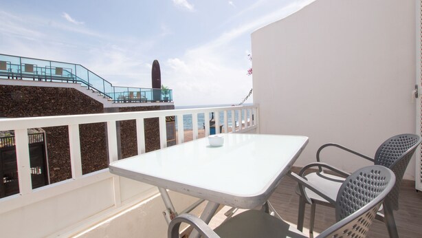 A balcony with a white table and chairs, a stone wall, and a view of the sea. - VM7, first floor. (El Cotillo)