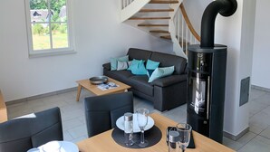 Una sala de estar moderna con un sofá, una mesa de comedor y un estufa de leña en madera negra.