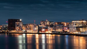 A waterfront cityscape at night with illuminated buildings reflecting on the water. - Quality Hotel Ramsalt (Bodo)