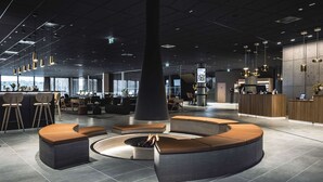A modern lounge area with a central fire feature, seating arrangements, and a reception desk. - Quality Hotel Ramsalt (Bodo)
