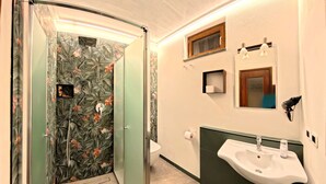 A bathroom with a shower, toilet, sink, and a mirror.