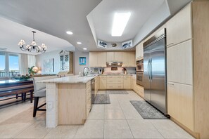 A modern kitchen with a large island, stainless steel appliances, and wooden cabinetry.