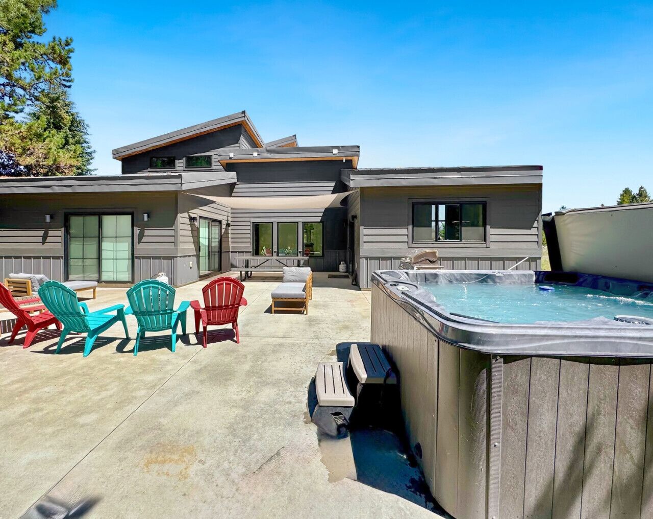 A modern house with a hot tub, outdoor seating, and a patio.