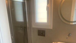 A bathroom with a glass-enclosed shower, a toilet, and a sink with a mirror. - Amazing Studio with Sea view in Mykonos (Mykonos)