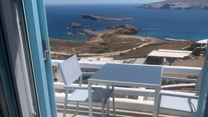 A balcony with a table and chairs, overlooking a coastal landscape with rocky terrain and the sea. - Amazing Studio with Sea view in Mykonos (Mykonos)